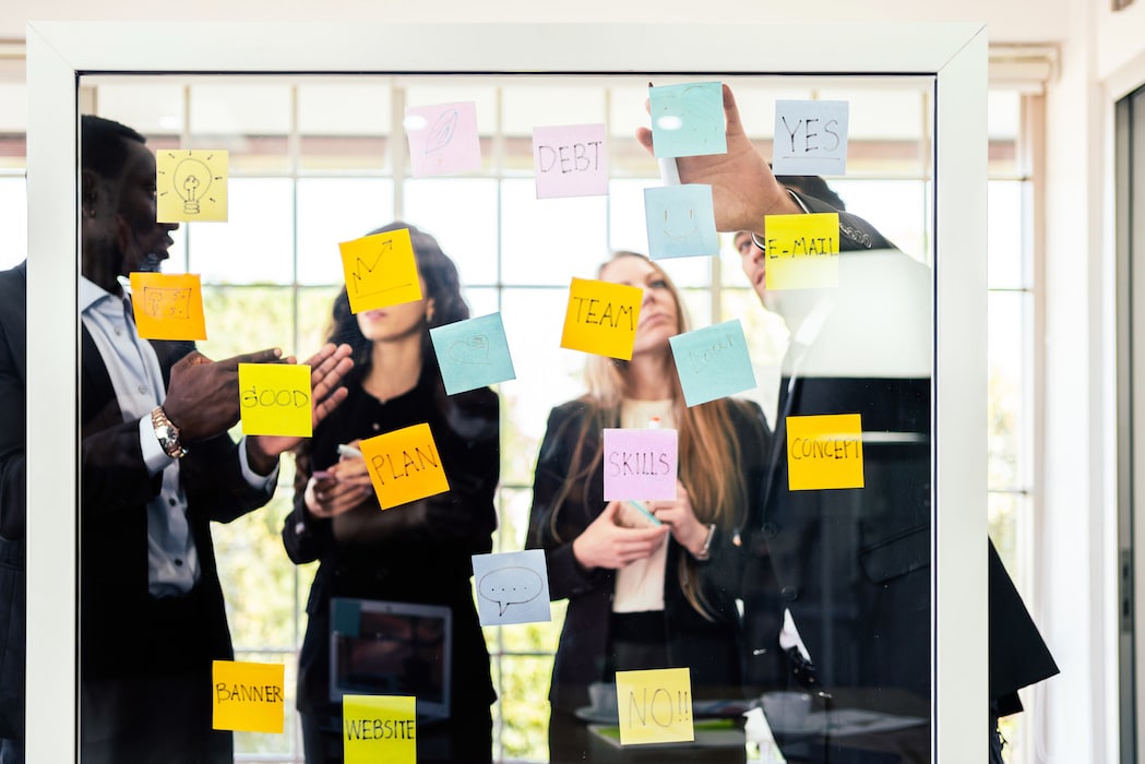 Group of successful business teamwork. Brainstorm meeting with colorful sticky paper note on glass wall for new ideas. Using agile methodology and do business. Brainstorming in a tech start-up office.