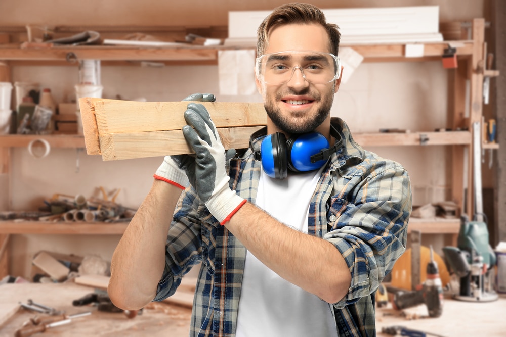 Carpenter,Holding,Wooden,Planks,At,Workshop