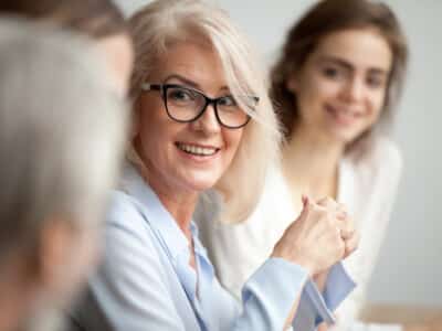 Smiling,Aged,Businesswoman,In,Glasses,Looking,At,Colleague,At,Team