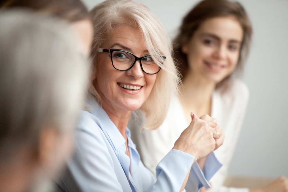 Smiling,Aged,Businesswoman,In,Glasses,Looking,At,Colleague,At,Team