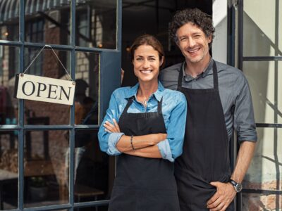Two,Cheerful,Small,Business,Owners,Smiling,And,Looking,At,Camera