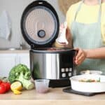 Woman,Preparing,Rice,In,Multi,Cooker,At,Kitchen,Table