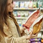 Woman,Comparing,Pet,Food,Packages,In,Pet,Store.,Responsible,Pet